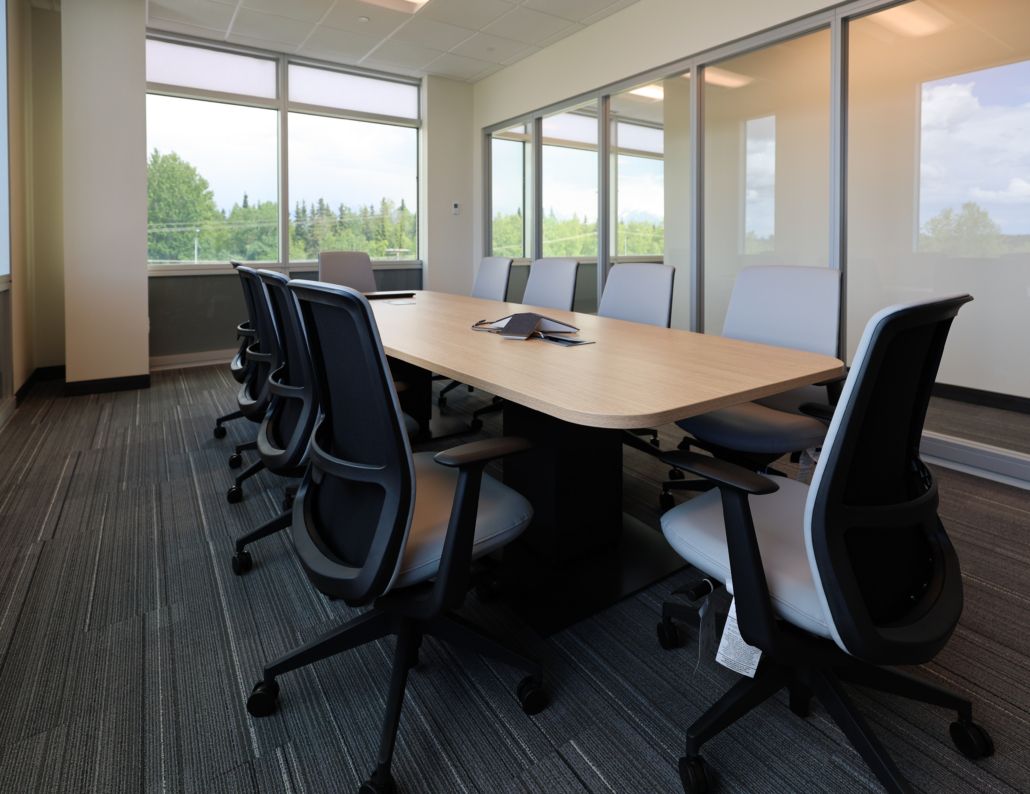 Edward Jones Anchorage office in SIRI building conference room with conference table that has integrated power / outlets, storage credenza, and 10 task chairs with modular glass wall store fronts and swing door