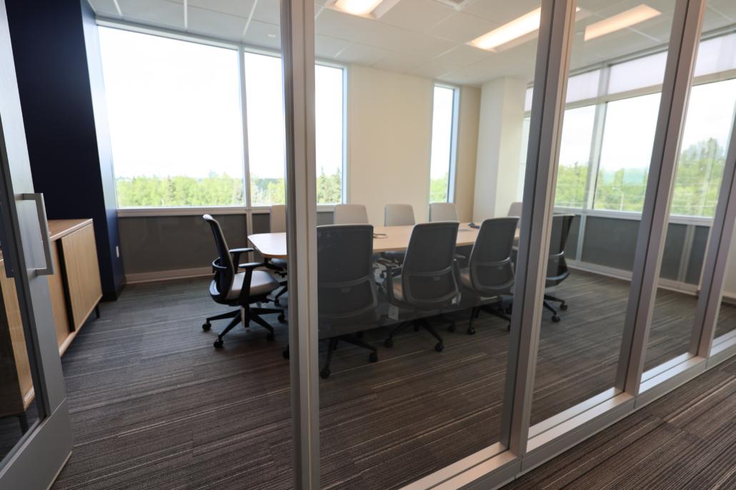 Edward Jones Anchorage office in SIRI building conference room with conference table that has integrated power / outlets, storage credenza, and 10 task chairs with modular glass wall store fronts and swing door